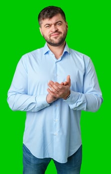 A man wearing a blue-striped shirt stands against a green background photo
