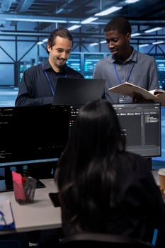 Cheerful teamworking engineers in data center looking for firewall misconfigurations affecting servers. Happy multiethnic employees checking systems bottlenecks leading to sluggish data transfer rates photo
