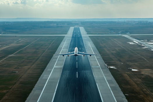 Airplane taking off from a runway under a cloudy sky in a vast landscape photo