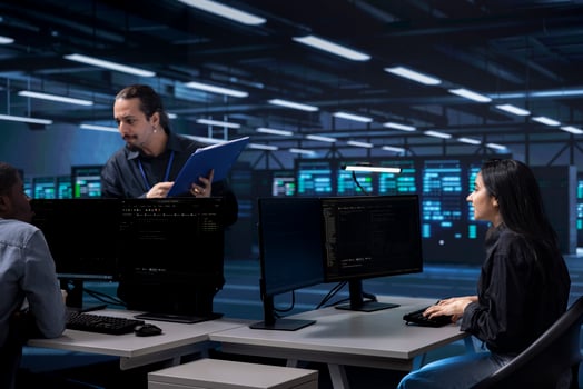 Multiethnic staff members in data center updating systems, protecting equipment from damaging software vulnerabilities. Diverse team of engineers looking for bugs causing infrastructure to slow down photo
