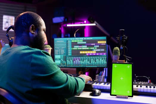Sound engineer composing new tunes with daw interface, operating on greenscreen display. African american skilled musician mixing and mastering his recordings, stereo console and gear. photo