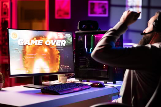 Upset gamer at desk frustrated after receiving game over screen, getting his spaceship destroyed in flying game. Sad player feeling gutted after losing science fiction videogame photo