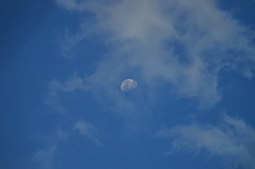 Half moon with blue sky and clouds background during the day. Blue sky background. photo