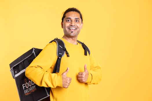 Portrait of cheerful man with thermal backpack doing thumbs up sign and smiling, excited to do job, studio background. Happy delivery person doing like hand gesture, going to client adress photo