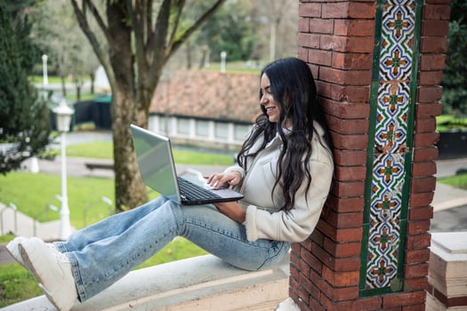young latin girl working with laptop outdoors photo
