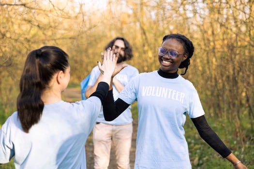 Satisfied diverse women sharing a high five feeling proud of their hard work to clean the natural habitat. Congratulating each other for showing perseverance and devotion. photo