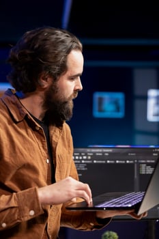 Computer engineer crosschecking between laptop and monitor, implementing security measures to protect company systems. IT worker comparing software code between notebook and PC photo