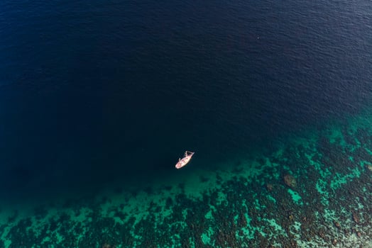 Scenic tropical sea with coral reef and boat sailing in summer photo