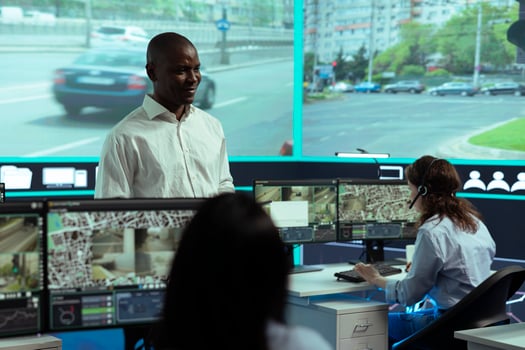 African american manager leads his staff to monitor the surveillance footage on CCTV system to learn about urban traffic dynamics. Diverse team working on public safety, satellite radar. photo