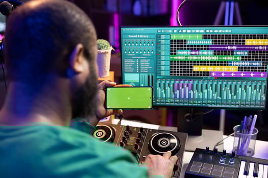 African american audio technician recording and editing tunes with pc software, looks at mockup chromakey display. Artist singer producing sounds for his new music, home studio. photo