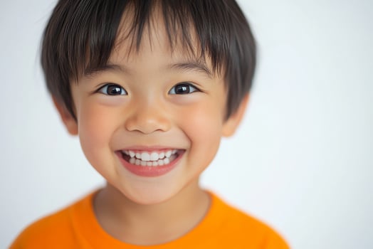 A young boy smiles while wearing an orange shirt photo