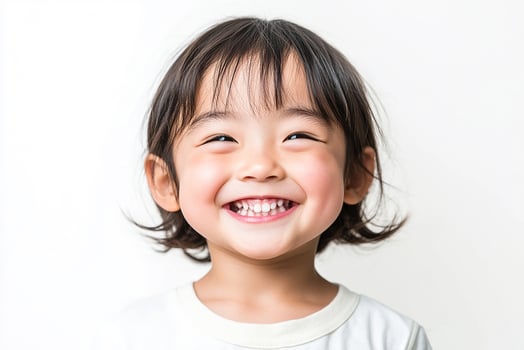 A little girl smiles while standing in front of a white background photo