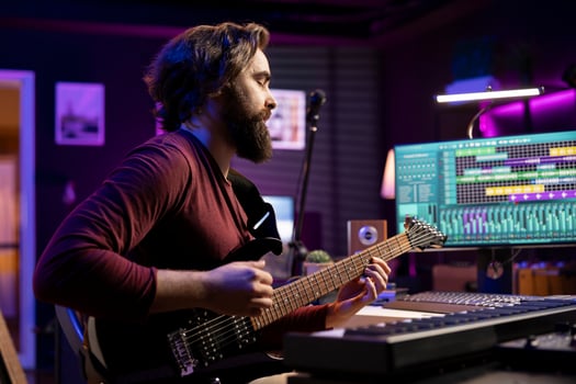 Musical performer playing guitar and recording his new tunes in home studio, using professional acoustical engineering gear. Skilled artist producing new sounds on acoustic instrument. photo