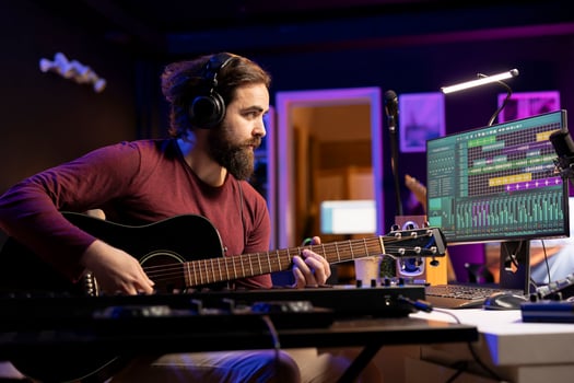 Composer singing a song on guitar and mixing the sounds on soundboard, working on editing audio recordings. Artist playing new accords on acoustic instrument, stereo equipment. photo