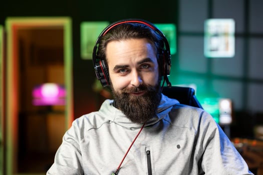Portrait of smiling man recording himself competing in videogame tournaments online while streaming on internet channel. Cheerful pro gamer participating in esports tourney during livestream photo