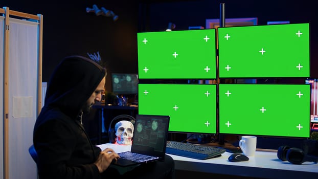 Man writing code on laptop in front of isolated screen PC monitors, trying to get past security systems. Hacker using chroma key computer and notebook to make scripts that can hack devices, camera B photo