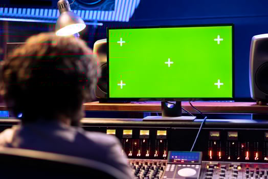 Music producer operates on control desk and mockup computer in professional studio, pressing key buttons and faders to create sounds. Young sound designer editing music and adding audio effects. photo