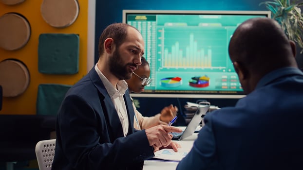 Accounting experts studying sales trends and market demands to ensure project success, looking into data infographics in executive meeting. Financial department team reviews revenue funds. Camera B photo
