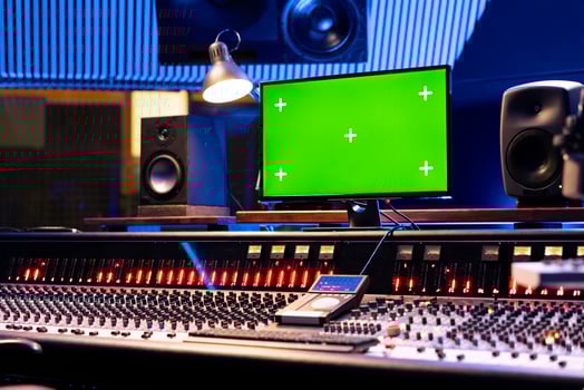 Mockup display on computer next to control desk soundboard, empty music recording studio with professional equipment and gear. Panel board with faders and knobs for post production. photo