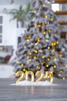 Golden figures number 2025 New Year against the background of tiny house with warm light and garlands. Greeting card, Happy New Year, cozy home photo
