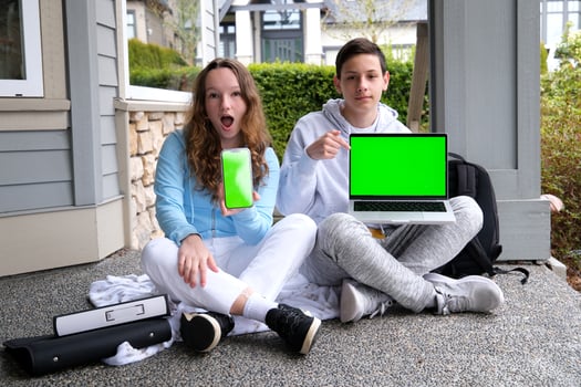 Cropped image of school kids preteen boys and girls elementary middle pupils sitting on the stairs and using digital devices wireless gadgets laptop tablet smartphone outdoors at the street photo