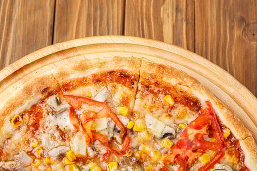 delicious pizza with chicken, mushrooms, cheese, tomatoes and corn on a wooden background photo