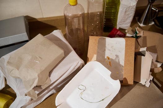 A cluttered kitchen counter full of discarded packaging and food containers photo