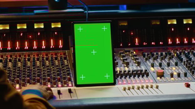 Audio expert processing sounds next to tablet with isolated mockup, working in post production with mixing console and technical gear. Producer pushing switchers and sliders. Camera A. photo