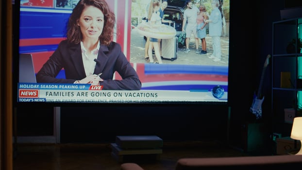 Anchorwoman on large TV screen showing reportage about summer vacations and family trips on VOD travelling channel. Widescreen television set left turned on in empty living room, close up shot photo