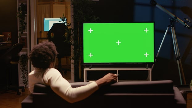 Person using chroma key projector to binge series on subscription based streaming services. Cord cutter relaxing on couch, enjoying on demand shows on mockup smart TV photo