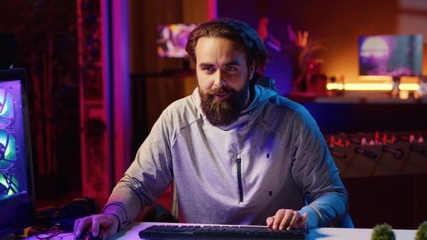 Content creator playing videogames live while chatting with online audience from neon lit apartment. Pro gamer streaming multiplayer game while discussing his strategies with viewers photo