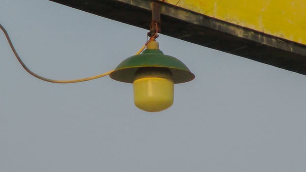 A yellow light hanging from a pole photo