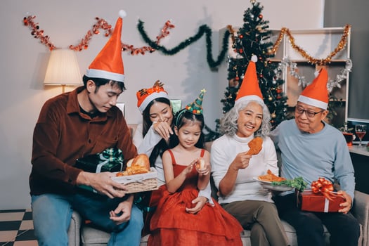 Portrait of Asian family exchanging presents during christmas at home. Attractive happy people holding gift box, celebrate holiday thanksgiving, xmas eve tradition in living room in house together. photo