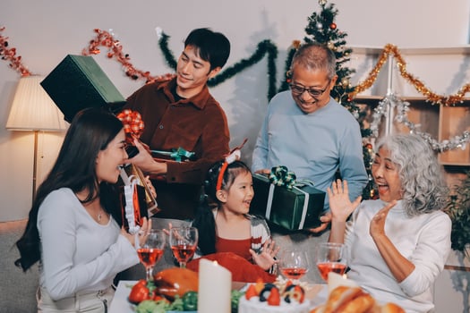 Portrait of Asian family exchanging presents during christmas at home. Attractive happy people holding gift box, celebrate holiday thanksgiving, xmas eve tradition in living room in house together. photo