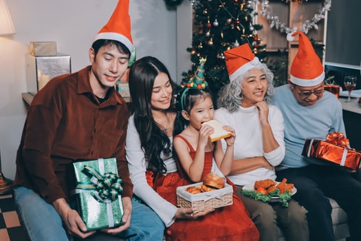 Portrait of Asian family exchanging presents during christmas at home. Attractive happy people holding gift box, celebrate holiday thanksgiving, xmas eve tradition in living room in house together. photo