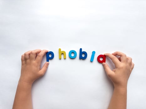 Childs hands spelling phobia with colorful letters on white background photo
