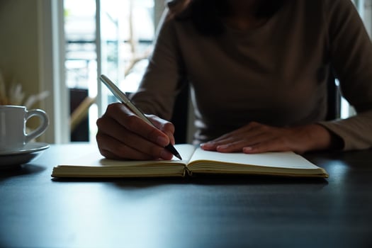 Selective Focus on Woman Hand Writing in a Journal Indoor photo