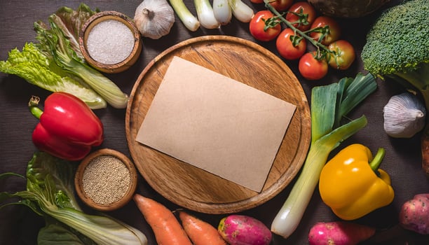 wooden plate with blank parchment paper surrounded by fresh vegetables including peppers and tomatoes photo
