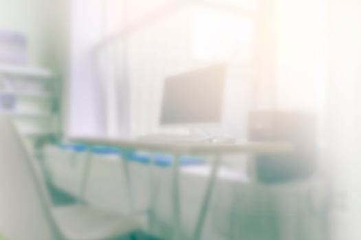 Blur office background with working desk and computer. Light is coming through the window. photo
