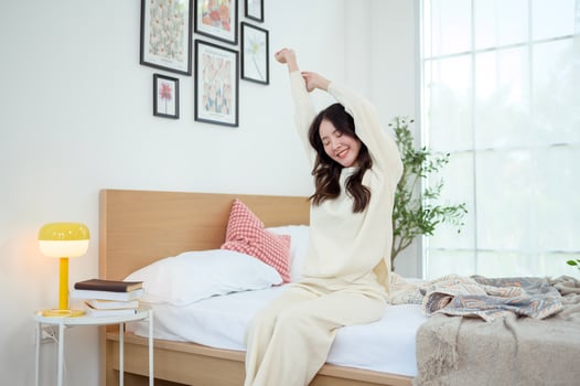 Young asian woman stretching in bed after Waking up in the Morning photo