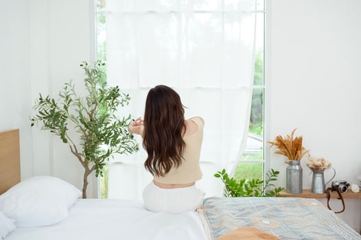 Young asian woman stretching in bed after Waking up in the Morning photo