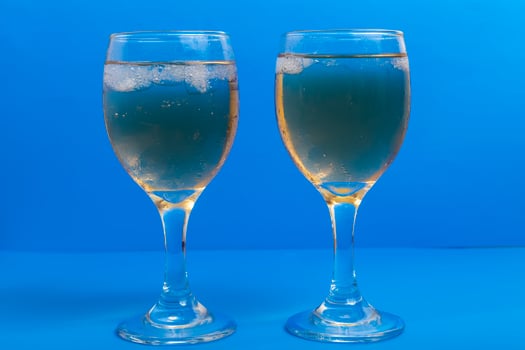 Close-up of two glasses of white wine with ice on a vibrant blue background photo
