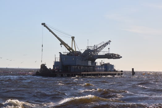 An Oil Rig situated in the vast Ocean with ongoing Crane Operations taking place photo