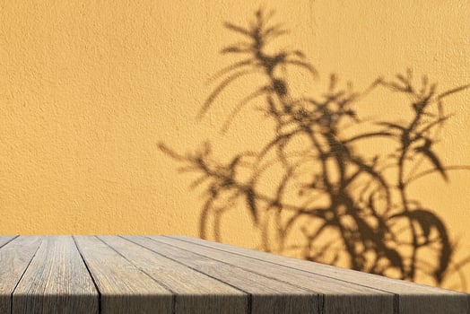 Wooden Table and Light Brown Concrete Wall Background with Leaves Shadow on Surface photo