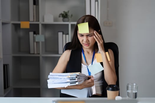 Focused Businesswoman Juggling Tasks in Modern Office Setting with Documents and Sticky Notes photo