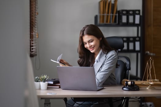 Young Businesswoman Analyzing Documents at Desk in Modern Office Setting with Laptop and Professional Attire photo