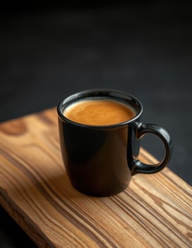 Rich espresso served in a black cup on a wooden board in a dark setting photo