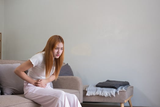 A young woman with stomach pain from diarrhea or menstrual cramps felt sick and touched her stomach with an unhappy expression. photo