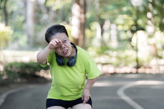 Exhausted Woman Jogging in Park with Headphones, Taking a Break on a Sunny Day photo