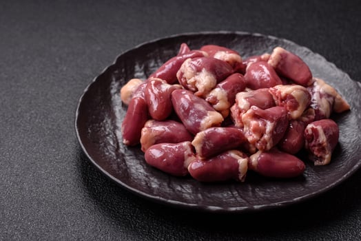 Raw chicken hearts with salt, spices and herbs photo